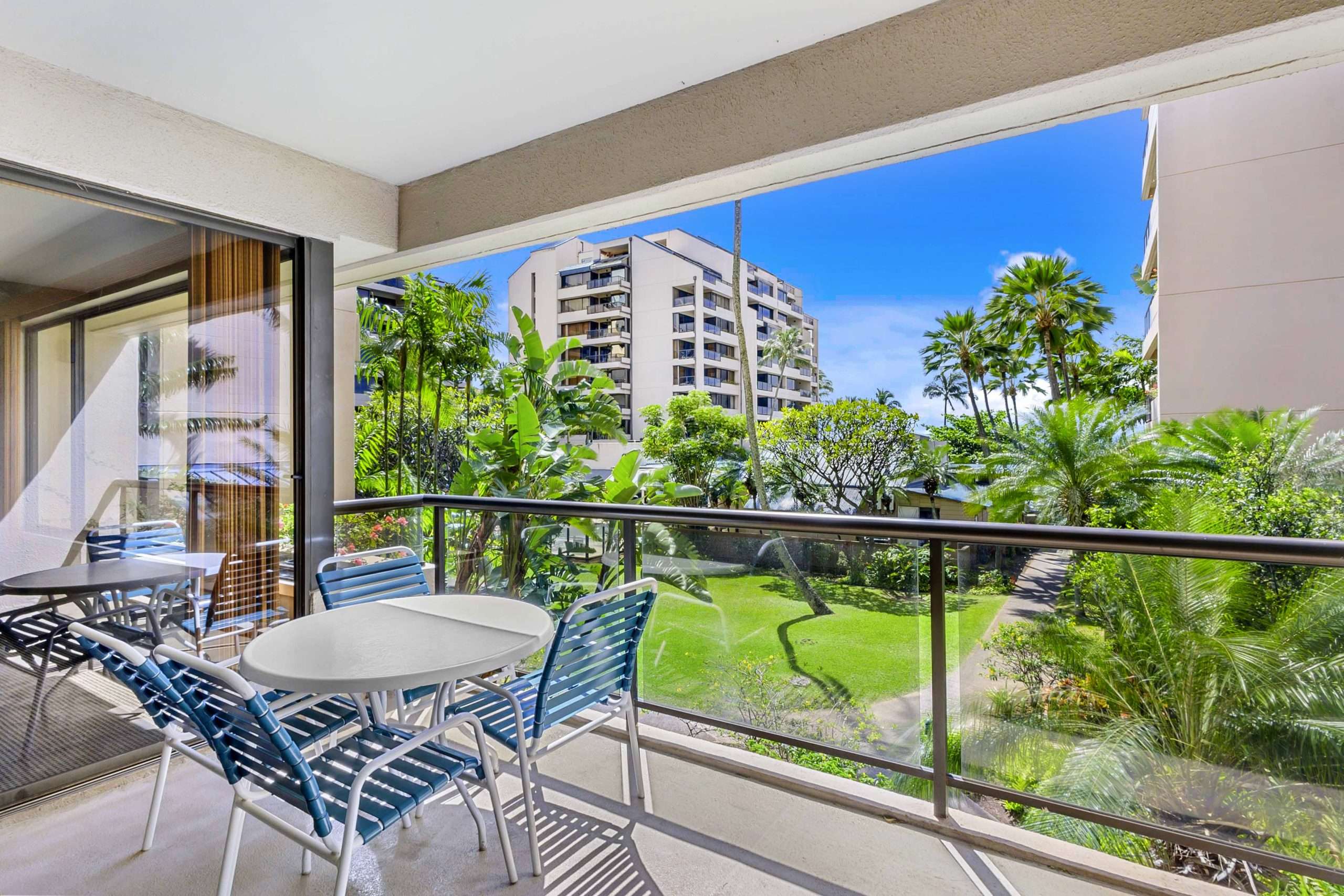 Resort suite patio with round table, chairs, and a scenic view of palm-lined grounds.