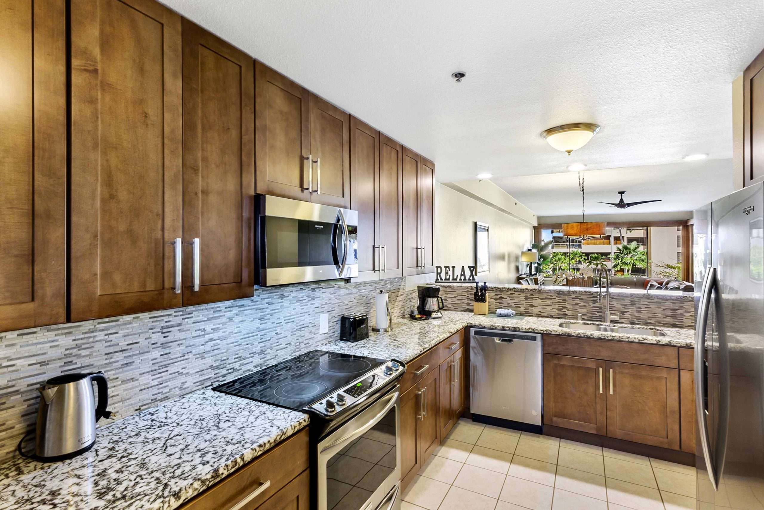 Fully equipped kitchen in a family suite, featuring wood cabinets, tiled backsplash, and a pass-through to the living area.