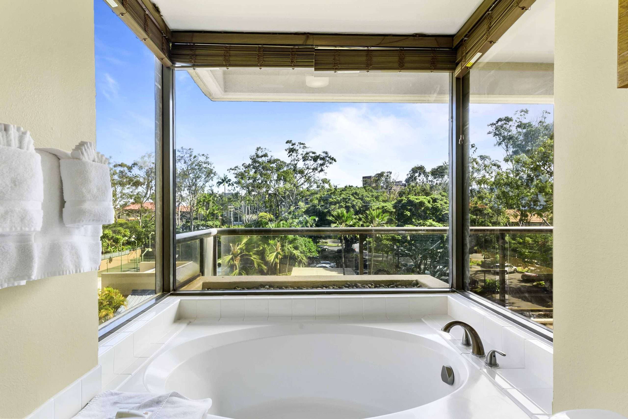 Corner jetted tub in a three-bedroom suite with floor-to-ceiling windows overlooking lush tropical gardens.