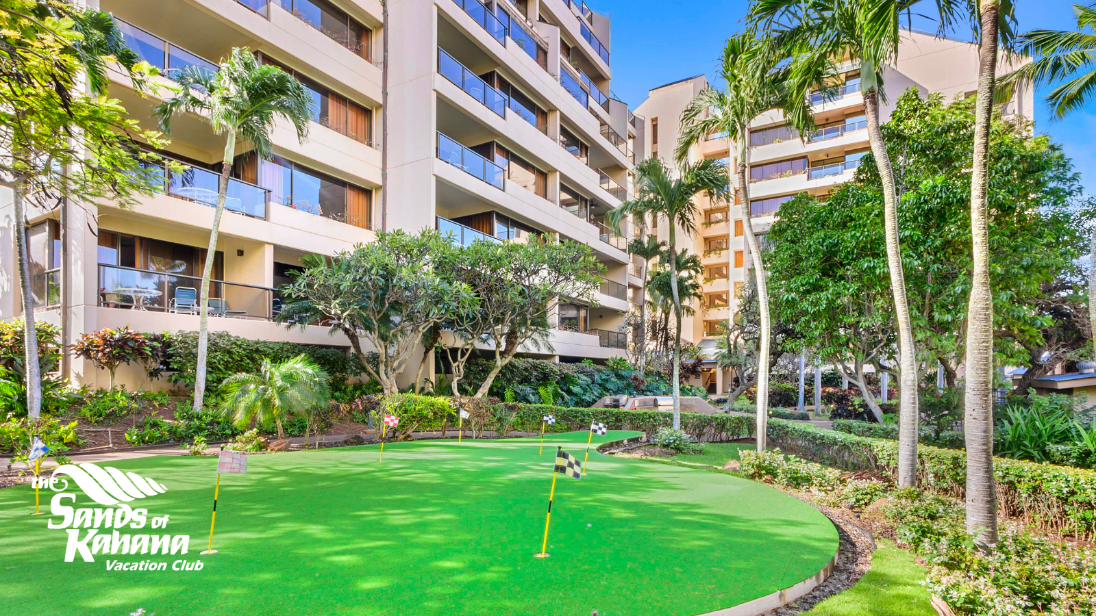 Sands of Kahana’s lush putting green with flags and resort balconies in the background.