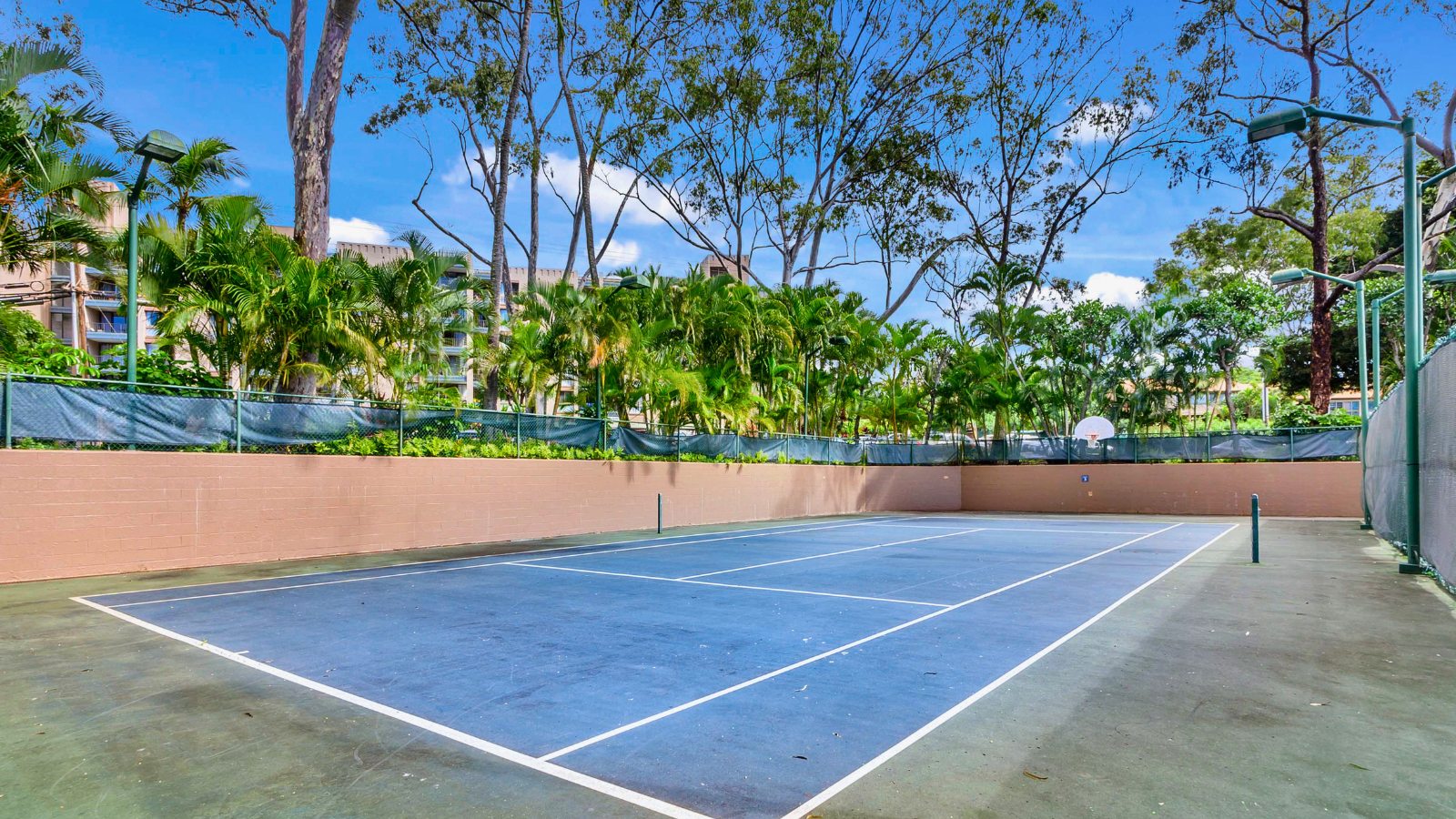 Sands of Kahana amenities: blue tennis court with adjacent basketball hoop and lush