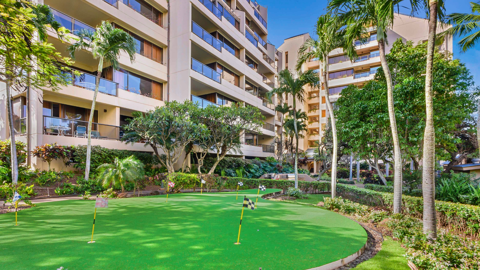 Sands of Kahana’s lush putting green with flags and resort balconies in the background.