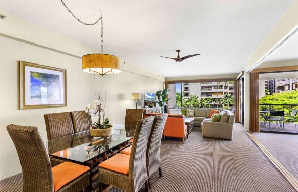 Three-bedroom family suite living and dining area with wicker chairs, sectional sofa, and garden-view balcony.